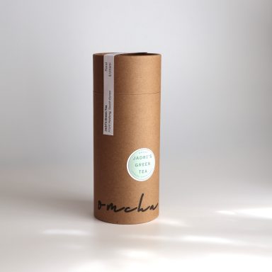 omcha tea tube packaging, a kraft recycled card tube with 'omcha' stamped onto it in black ink. A green label reads 'Jadri's green tea'