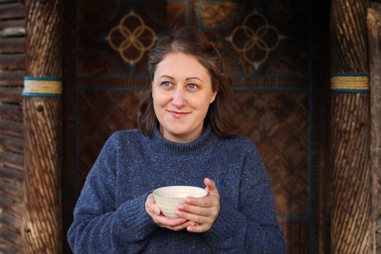 Meg smiling and holding a bowl of tea with both hands